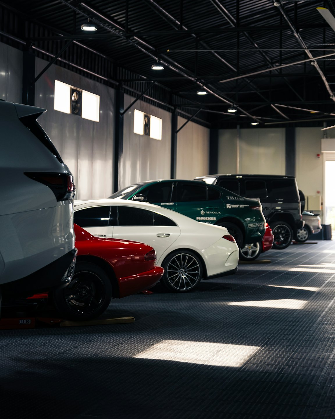 Modern cars parked in a neat row inside an indoor garage.