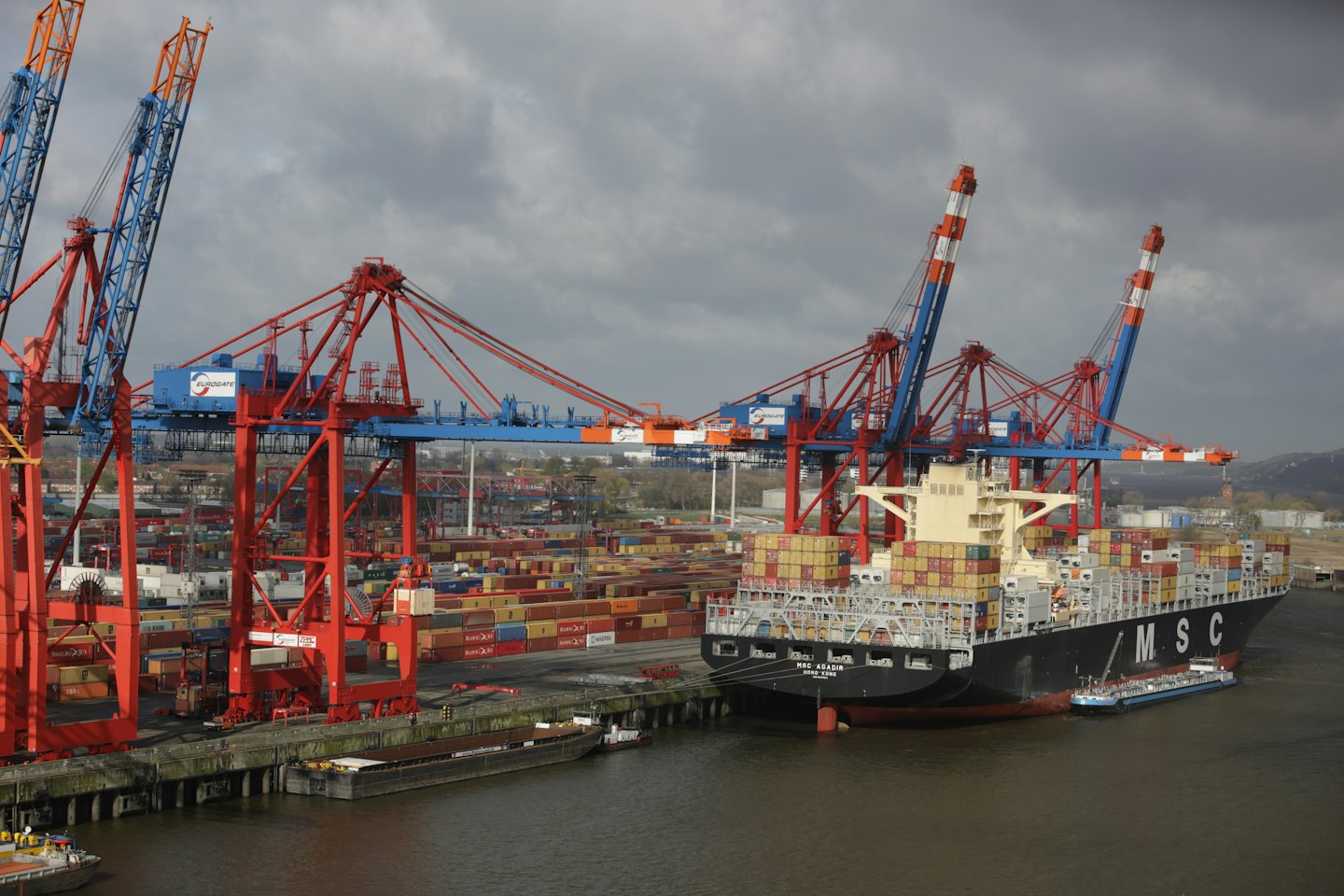 Container ship being loaded by gantry cranes at a busy port.